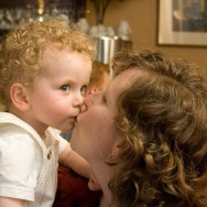 A baby kisses his mother at a first communion celebration